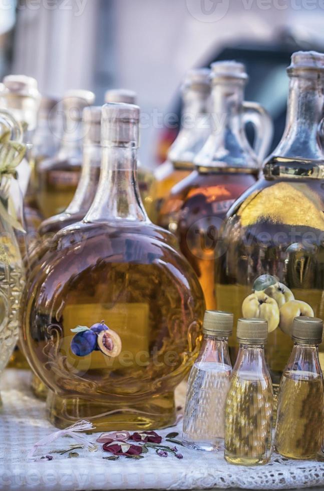 brandies balcánicos tradicionales en las botellas en el puesto del mercado foto