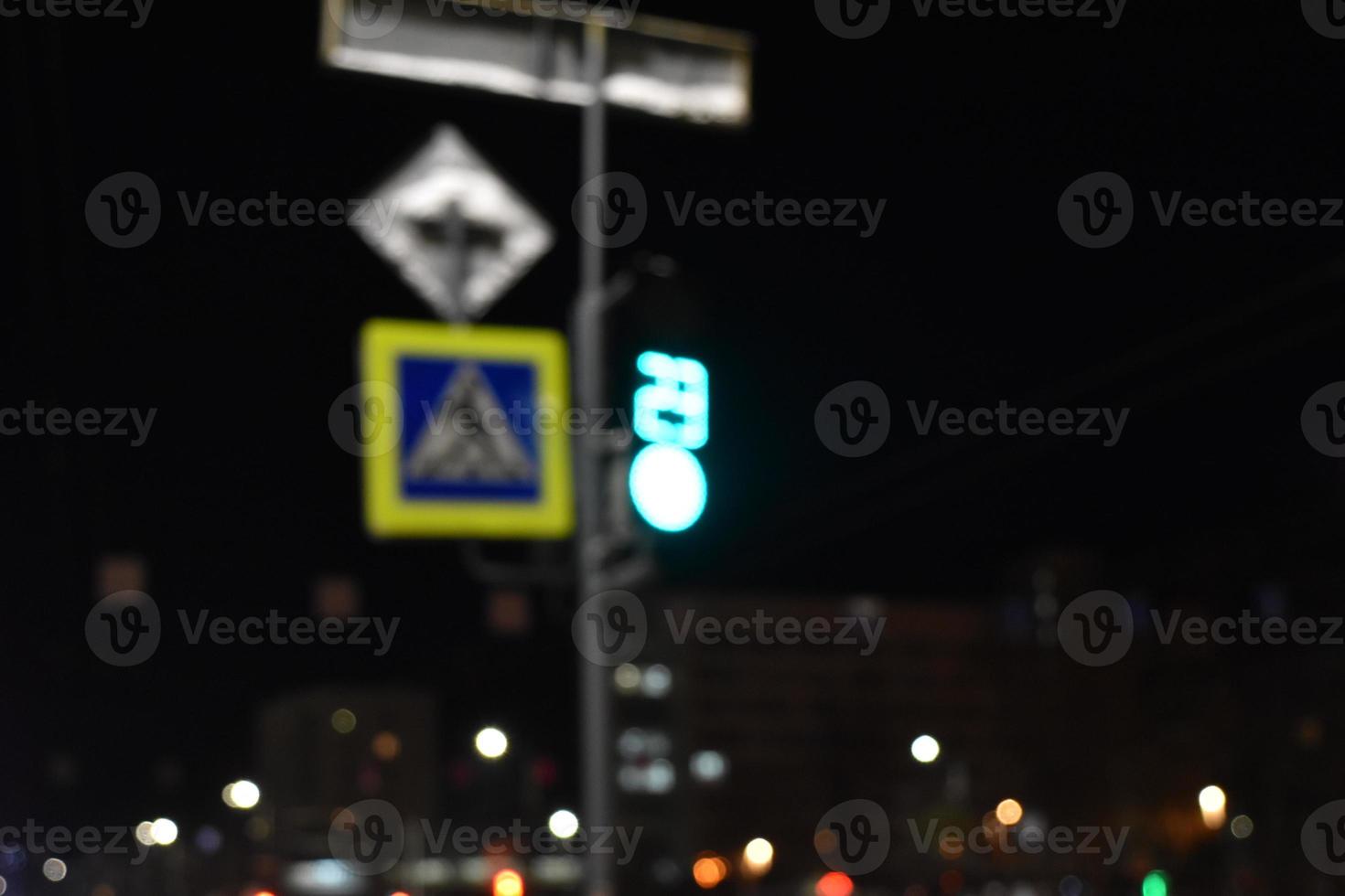 The sign of the road crossing and the lights of the night city. photo