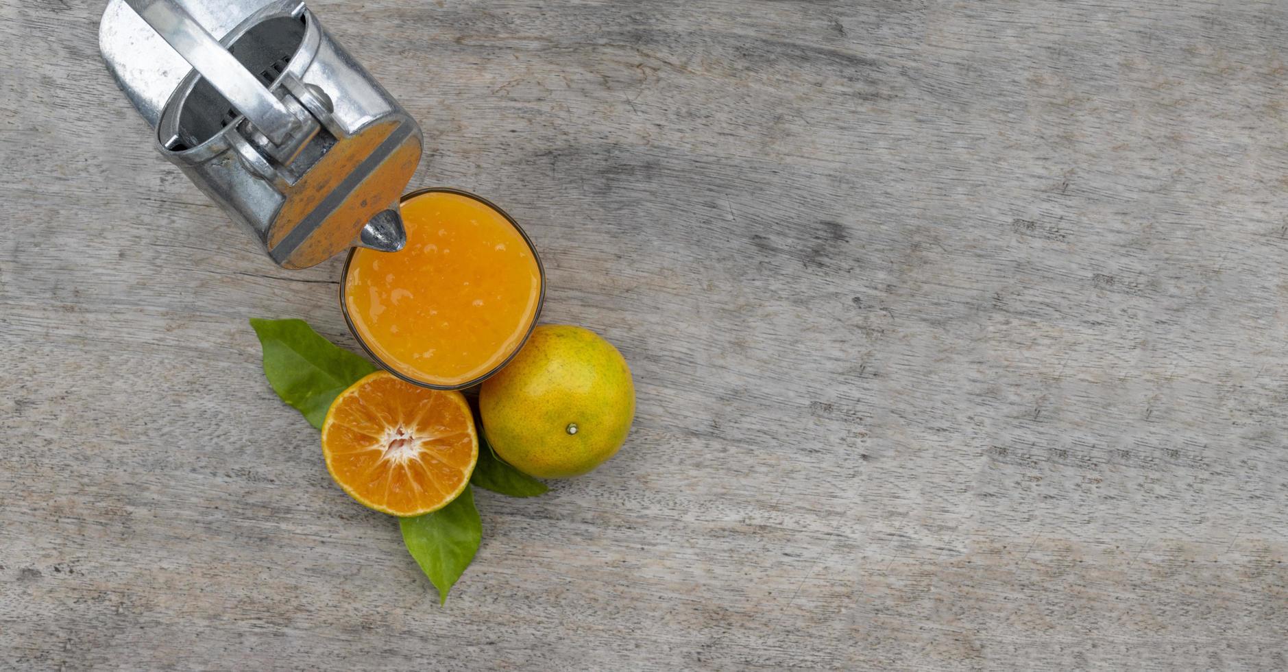 Orange juice in glass and fresh citrus around with Juicer hand press squeezer fruit on wood table photo