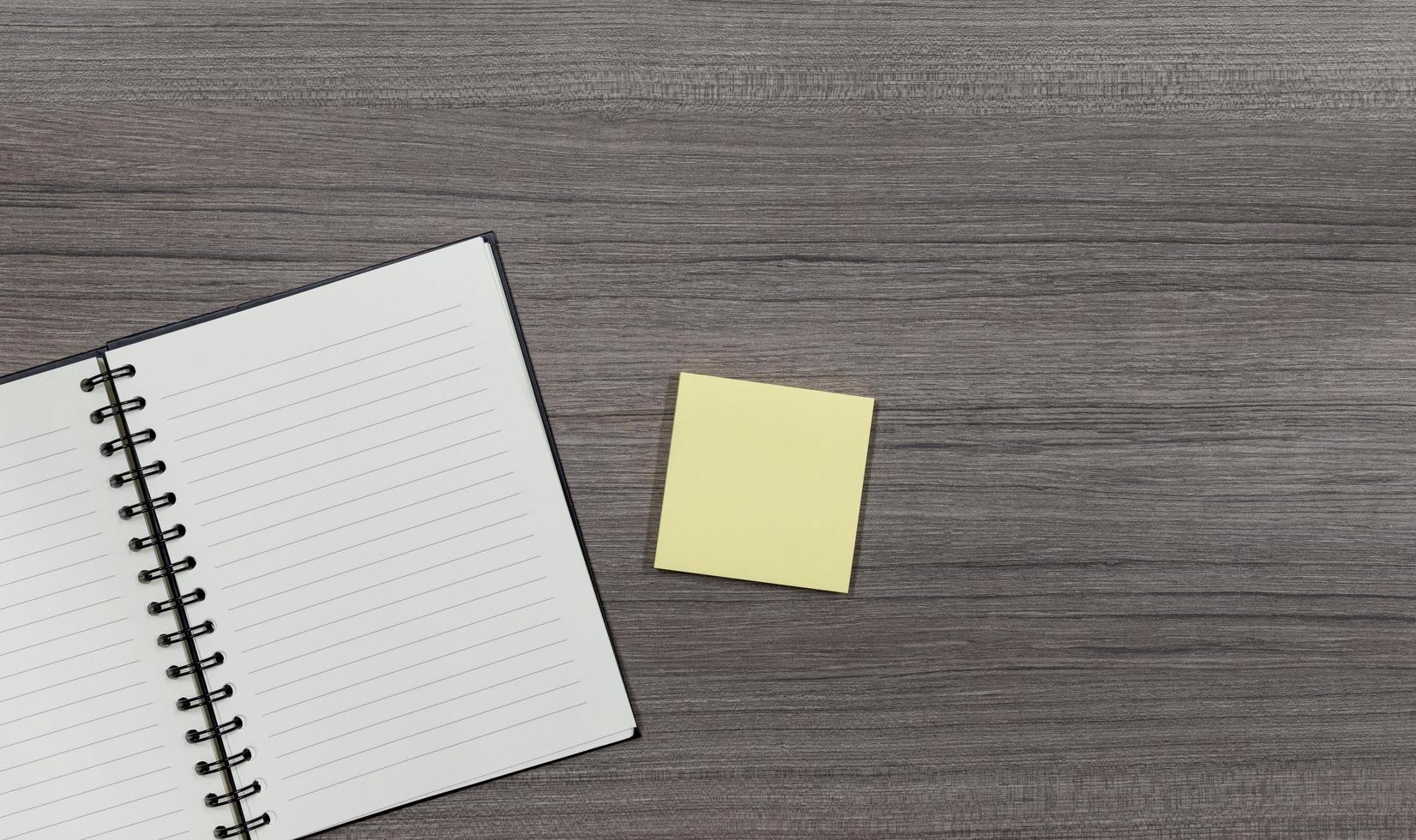Top view notebook and yellow notice paper on wooden floor with copy space photo