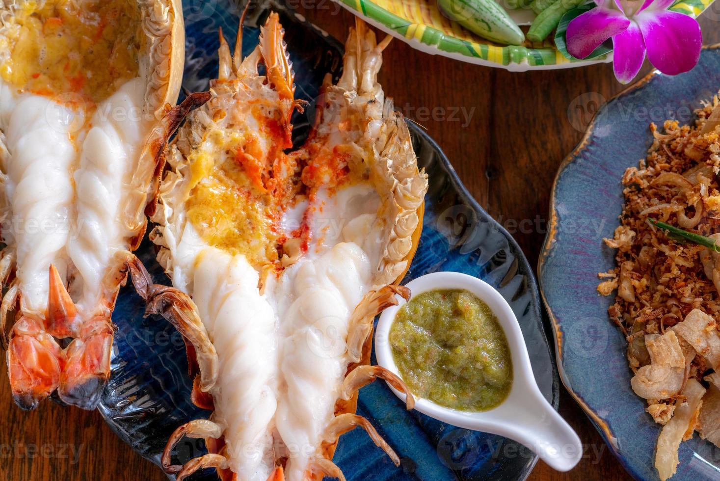 Grilled giant river prawn in a Thai luxury restaurant. Seafood in Thailand. Grilled giant river prawn served on a plate with Thai seafood sauce. Thai cuisine. Grilled giant shrimp on a dinner table. photo