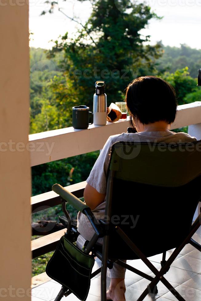 Silhouette women person relax alone on a chair and enjoy tropical nature in the morning with coffee time, holiday vacation,life freedom concept. photo