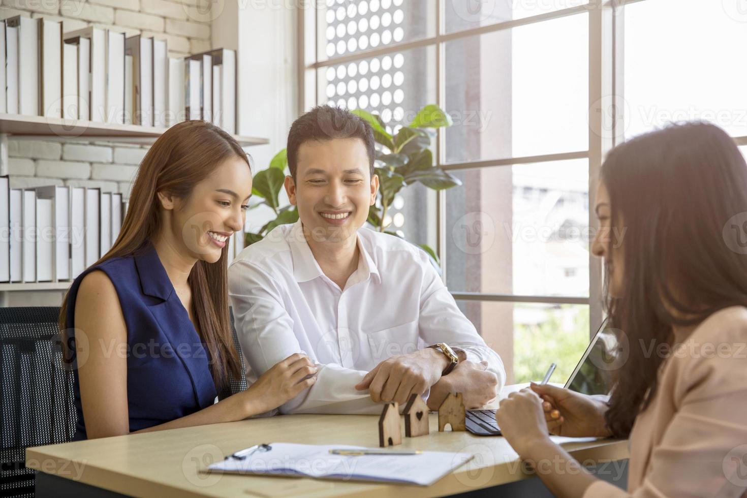 feliz joven pareja amorosa hablando con su agente inmobiliario con una sonrisa mirando la casa, planeando el futuro del concepto familiar foto