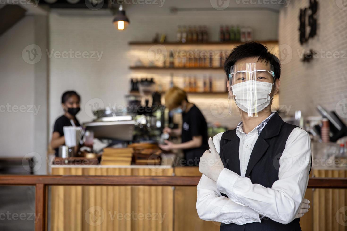 El dueño de una tienda de café y restaurante expresó su confianza en prevenir el covid-19, o el coronavirus, usando una máscara facial y guantes. concepto proteger covid19 foto