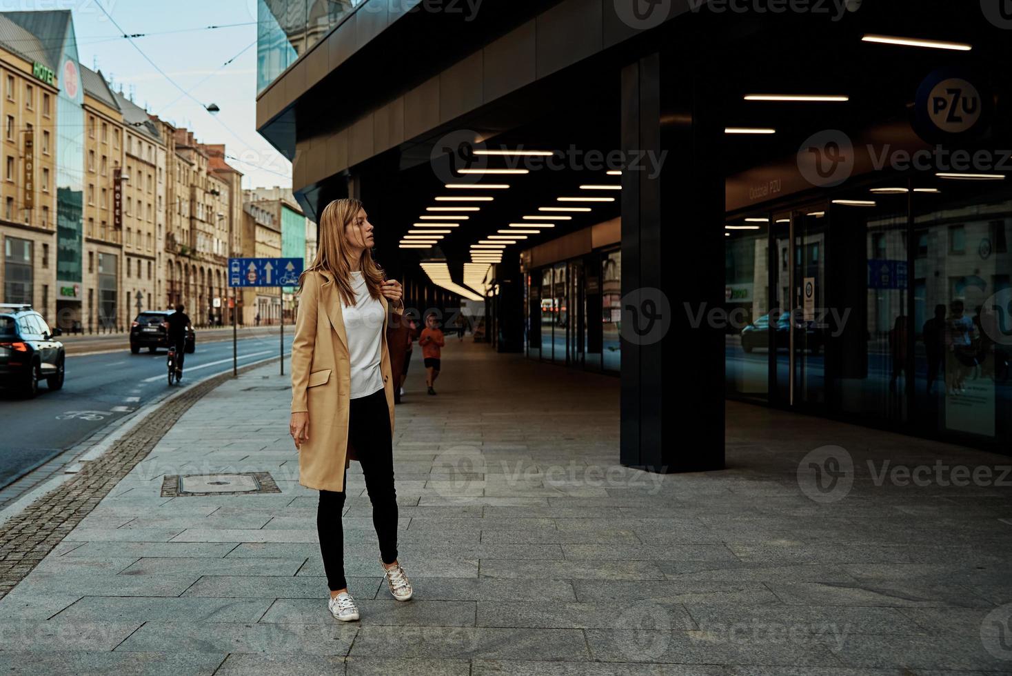 Woman in coat walks at city stret photo