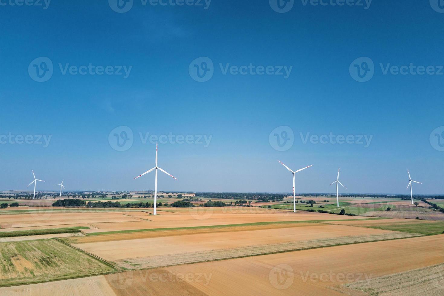 Windmill turbine in the field at summer day. Rotating wind generator photo