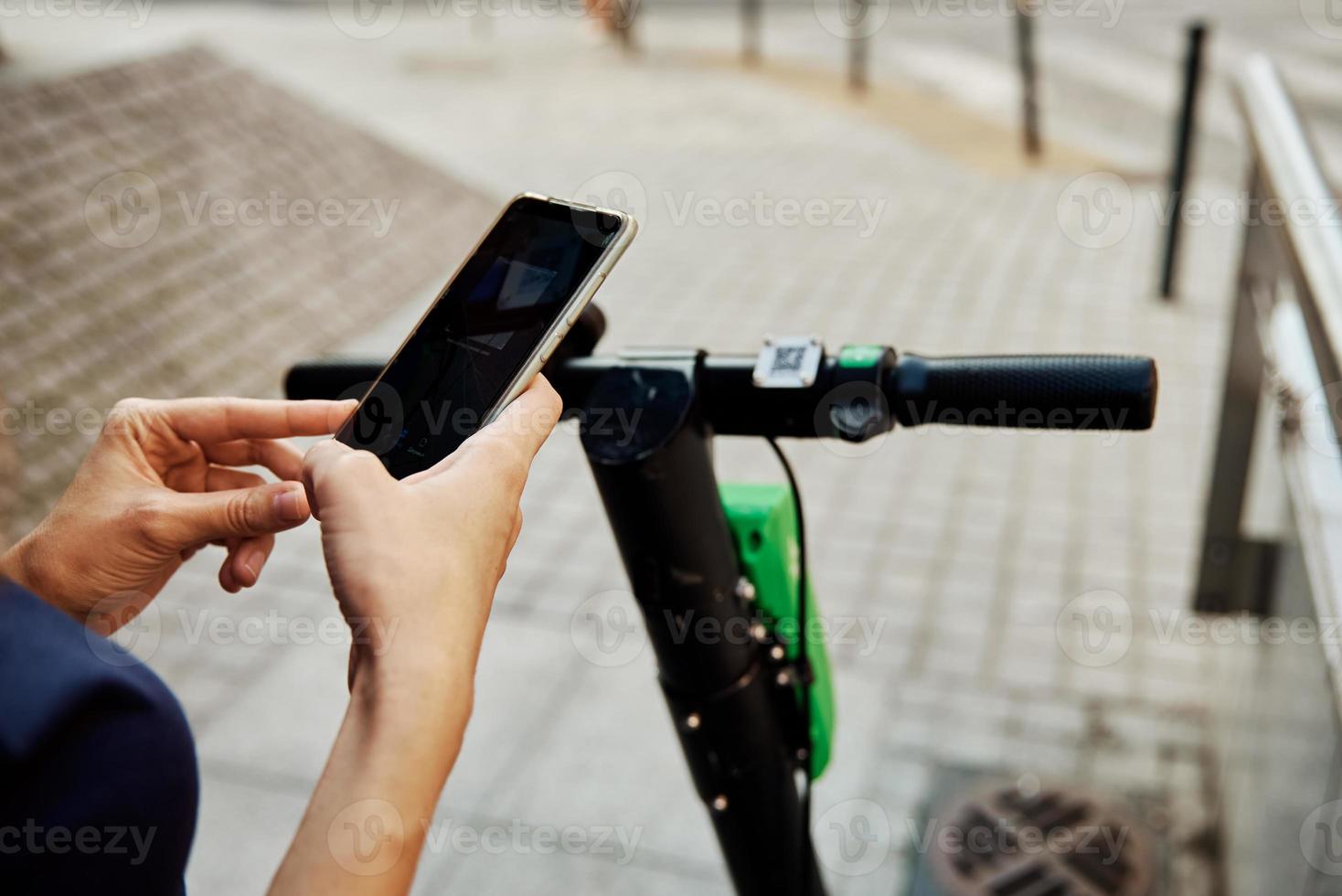 Woman unlock electric scooter for rent with a smartphone application photo