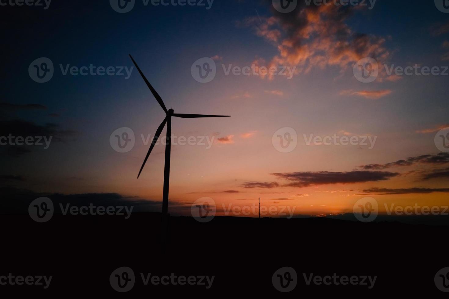 Windmill silhouette at sunset sky. Wind turbine generator photo