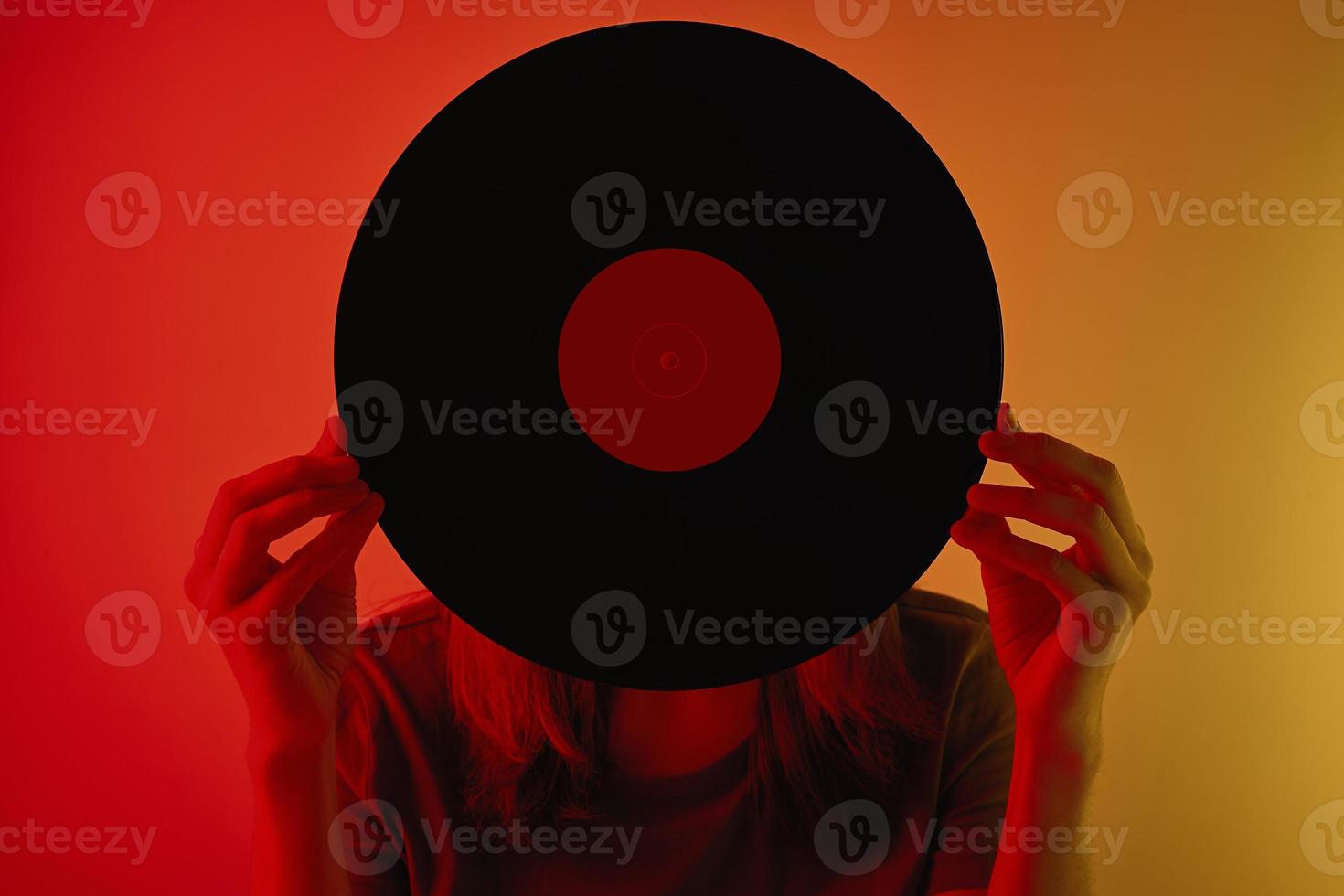 Woman covered her face with retro vinyl disc, toned photo