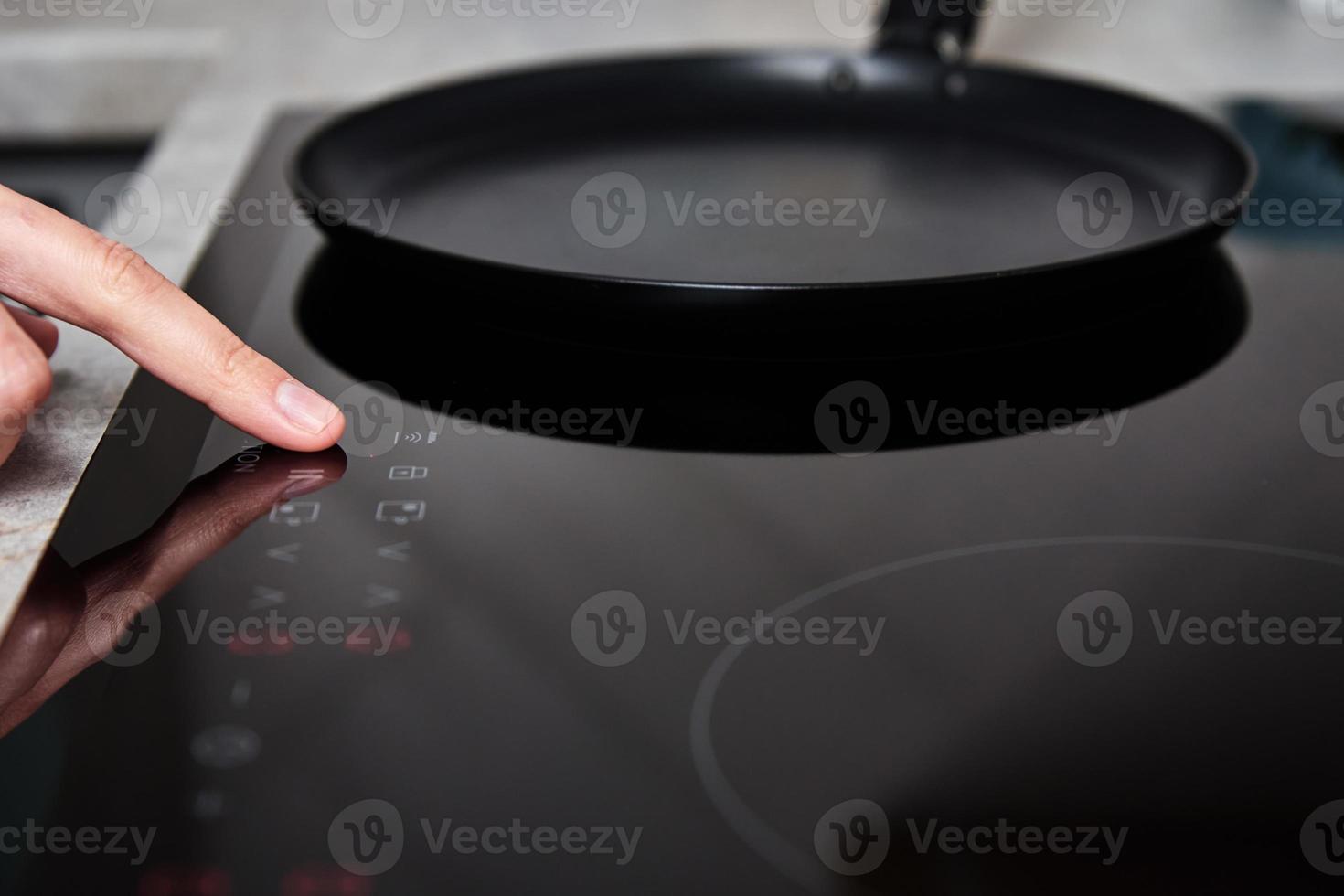 Woman hand turns on modern induction stove in the kitchen photo