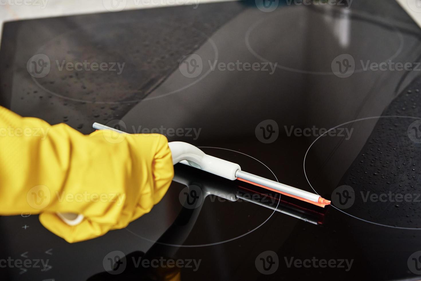 Woman in rubber gloves cleaning induction stove photo