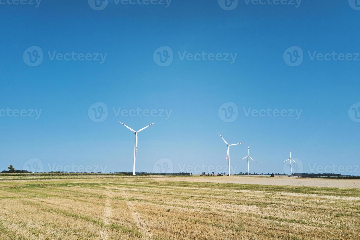 Windmill turbine in the field at summer day. Rotating wind generator photo