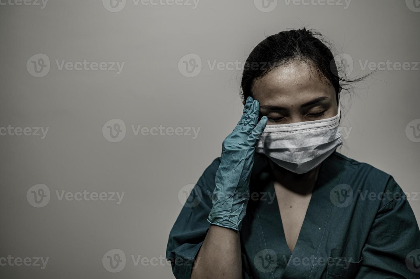 una enfermera asiática cansada y deprimida usa una máscara facial uniforme azul sentada en el piso del hospital, una joven doctora estresada por el trabajo duro foto