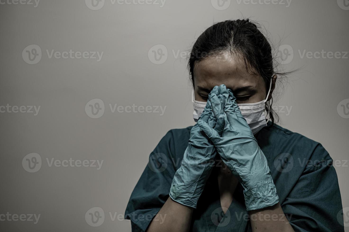 Tired depressed female asian scrub nurse wears face mask blue uniform sits on hospital floor,Young woman doctor stressed from hard work photo