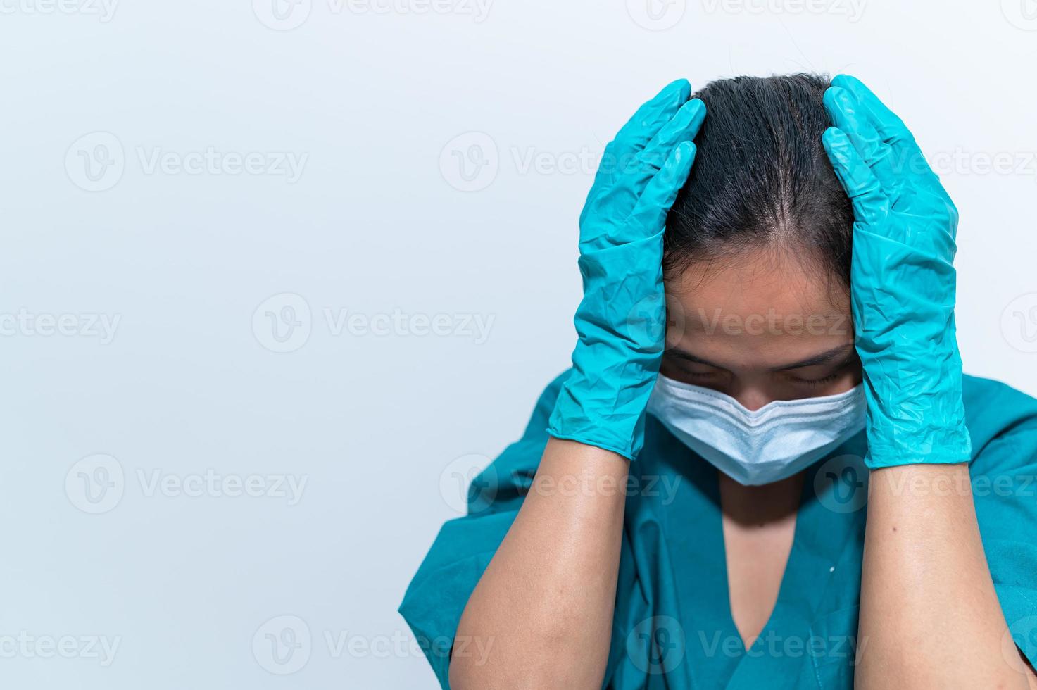 una enfermera asiática cansada y deprimida usa una máscara facial uniforme azul sentada en el piso del hospital, una joven doctora estresada por el trabajo duro foto