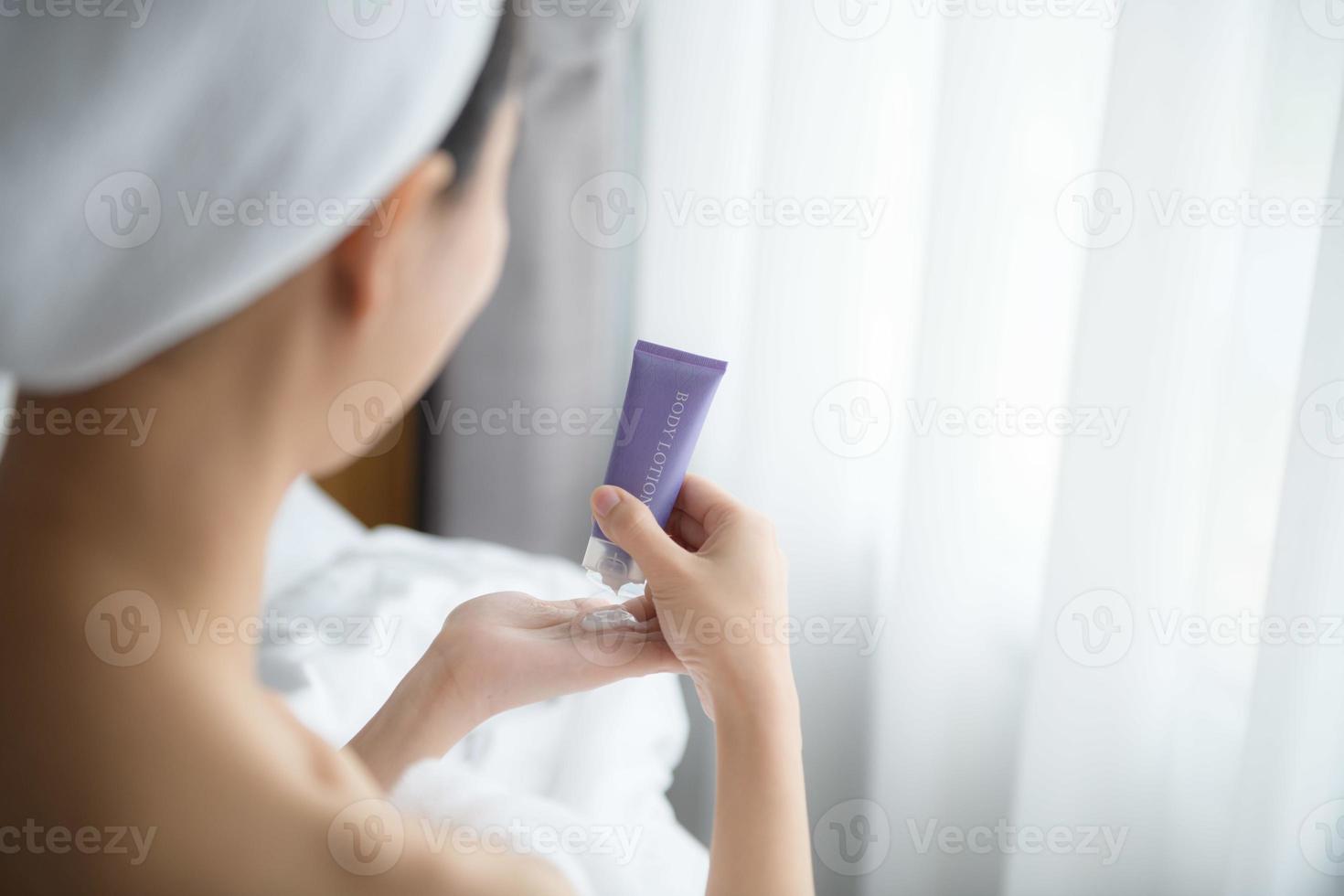 primer plano de mujeres que aplican crema de loción corporal en la mano. foto