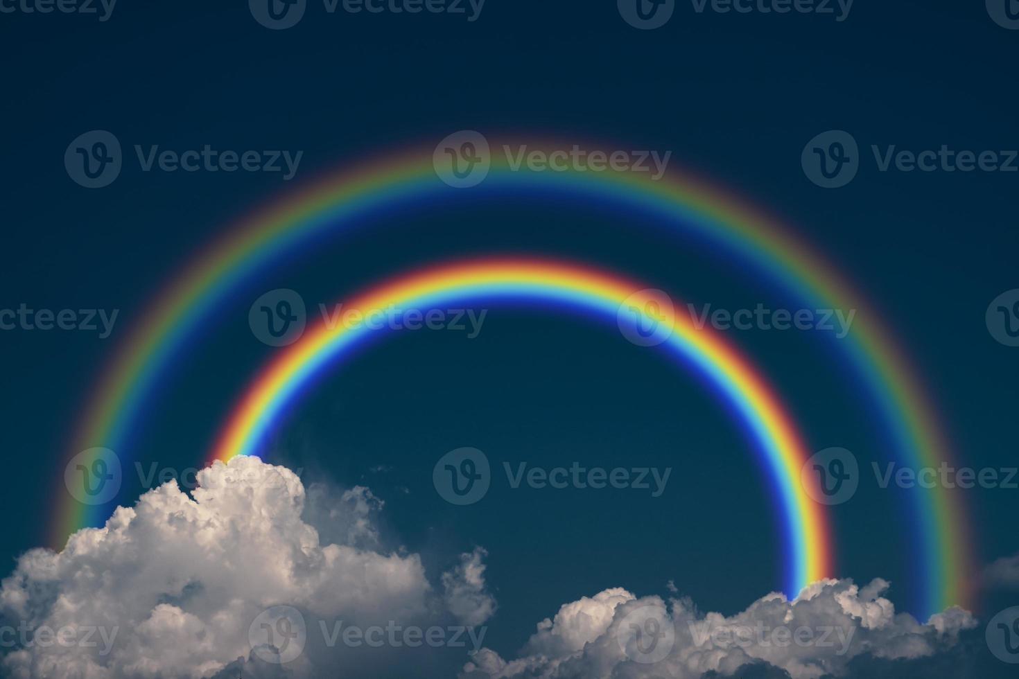 Primary rainbow and secondary rainbow back dark cloud on the sky photo