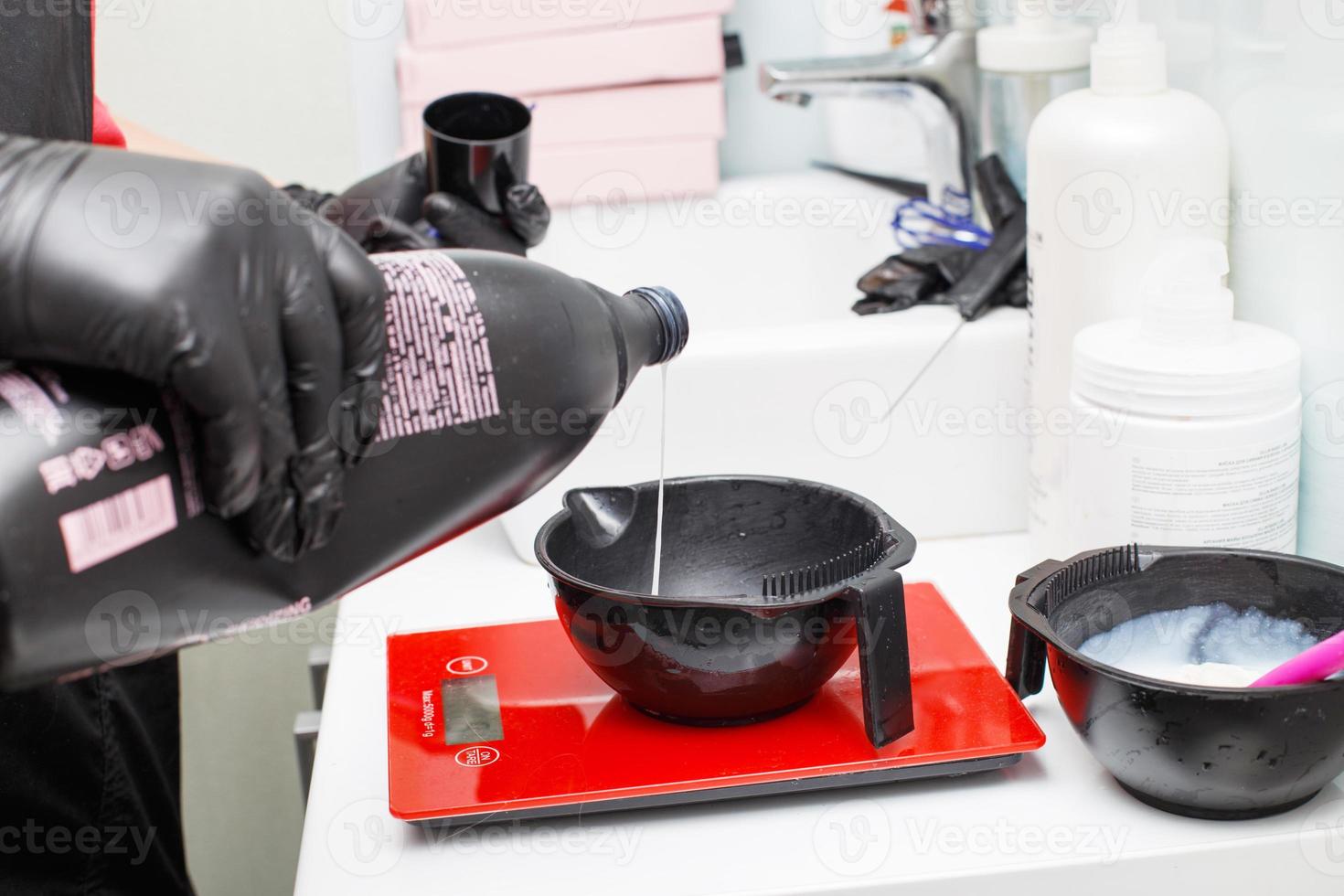 hairdresser holding bowl and preparing hair dye in beauty salon close. photo