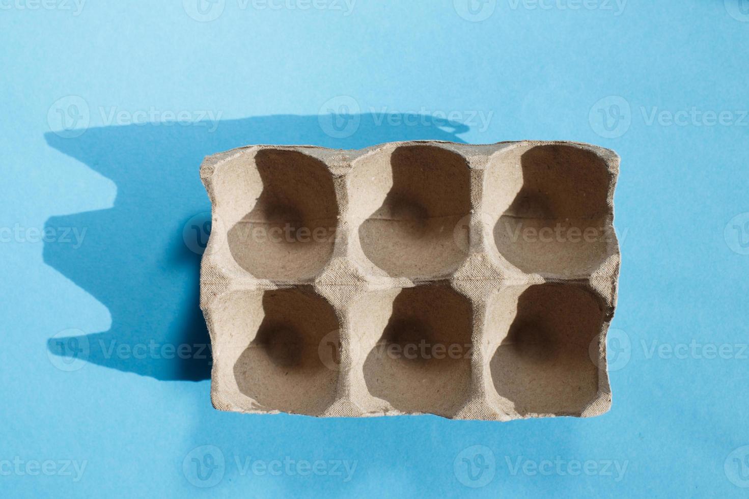 Empty eggs carton box with hard shadows on blue background. photo