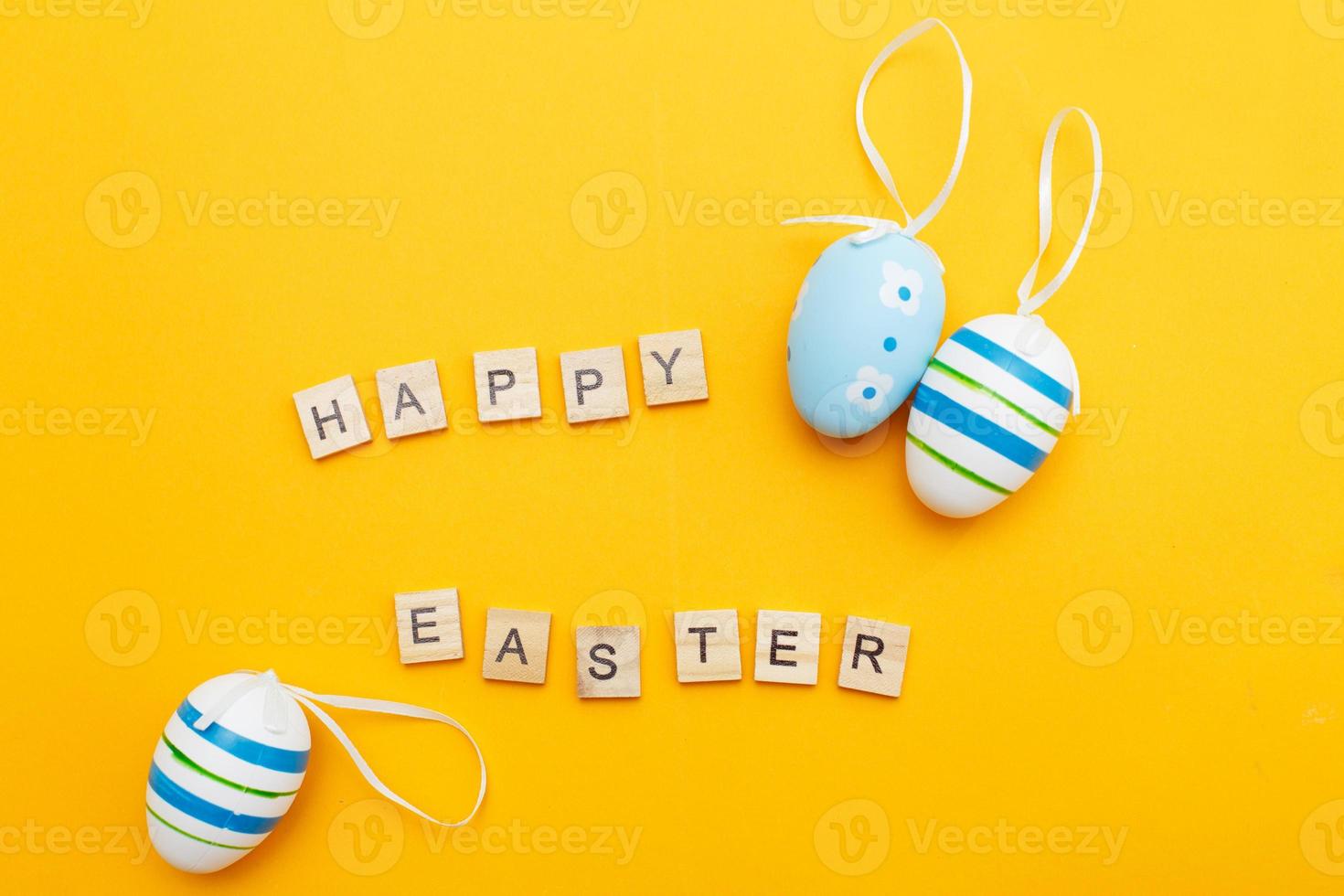 inscription happy easter with colorful handmade painted blue eggs on orange background photo