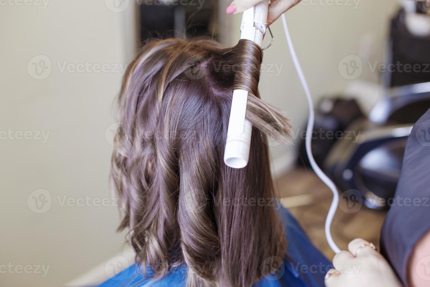 hairdresser doing a curling iron to a client in a beauty salon photo