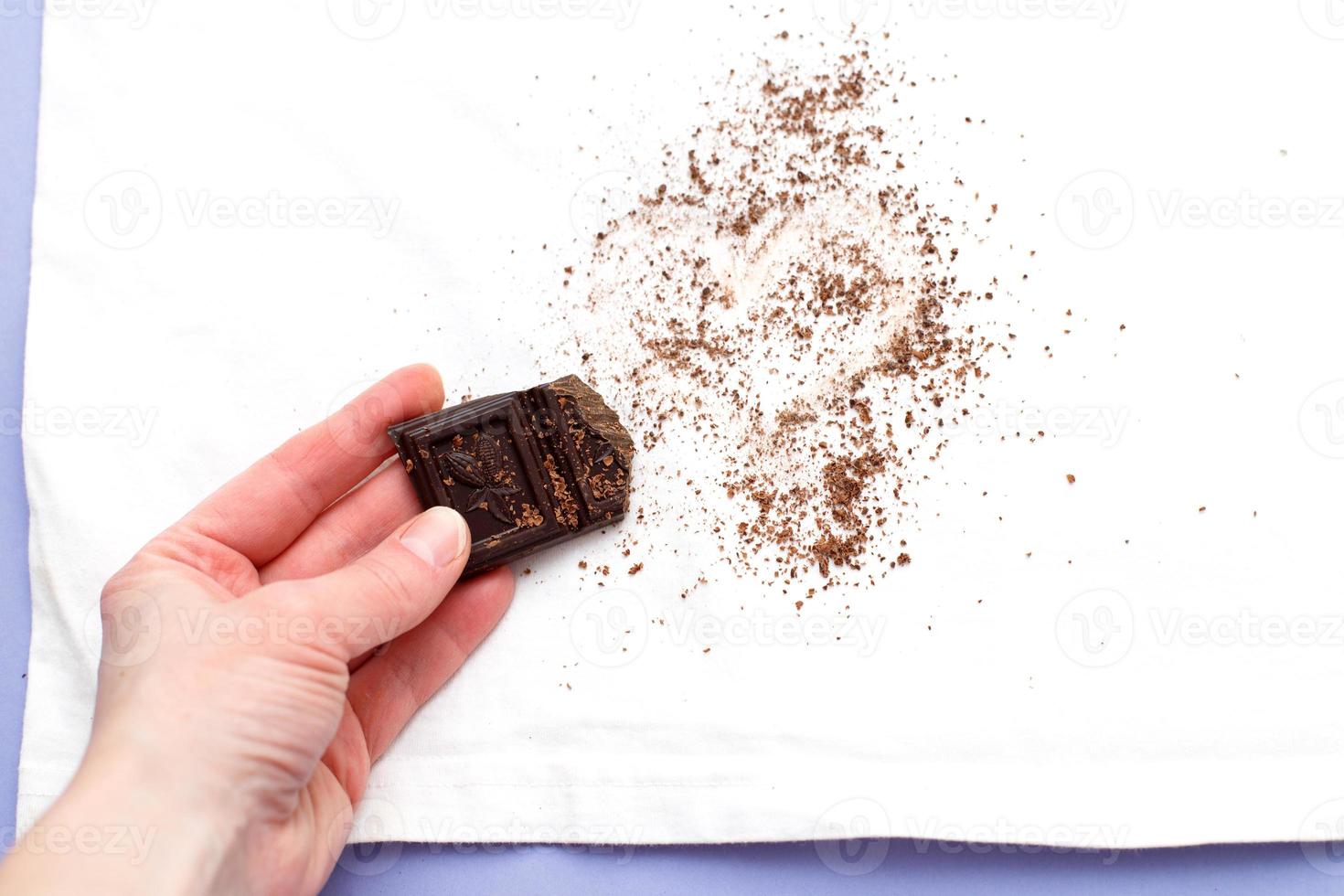 female hand holding white clothes with ditry stains from chocolate on purple very peri background photo