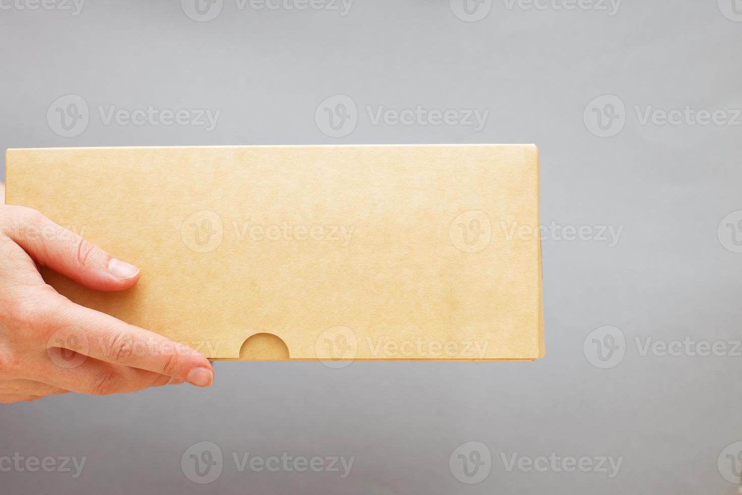 human hands holding delivers carton box on grey background. Delivery and online shopping concept. photo
