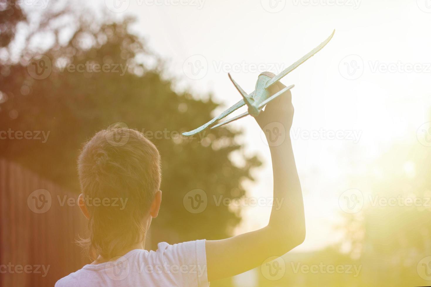 Happy child boy playing with toy airplane outdoor at sunset photo