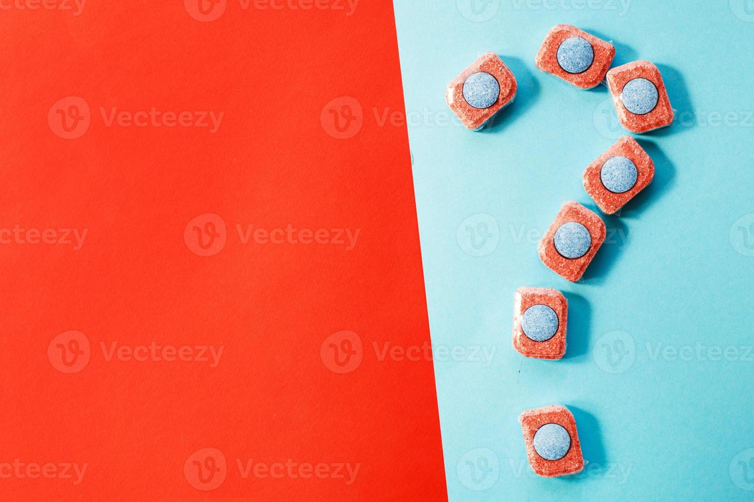 capsules for kitchen dishwashers and a question mark on a blue and red background. flat lay. photo