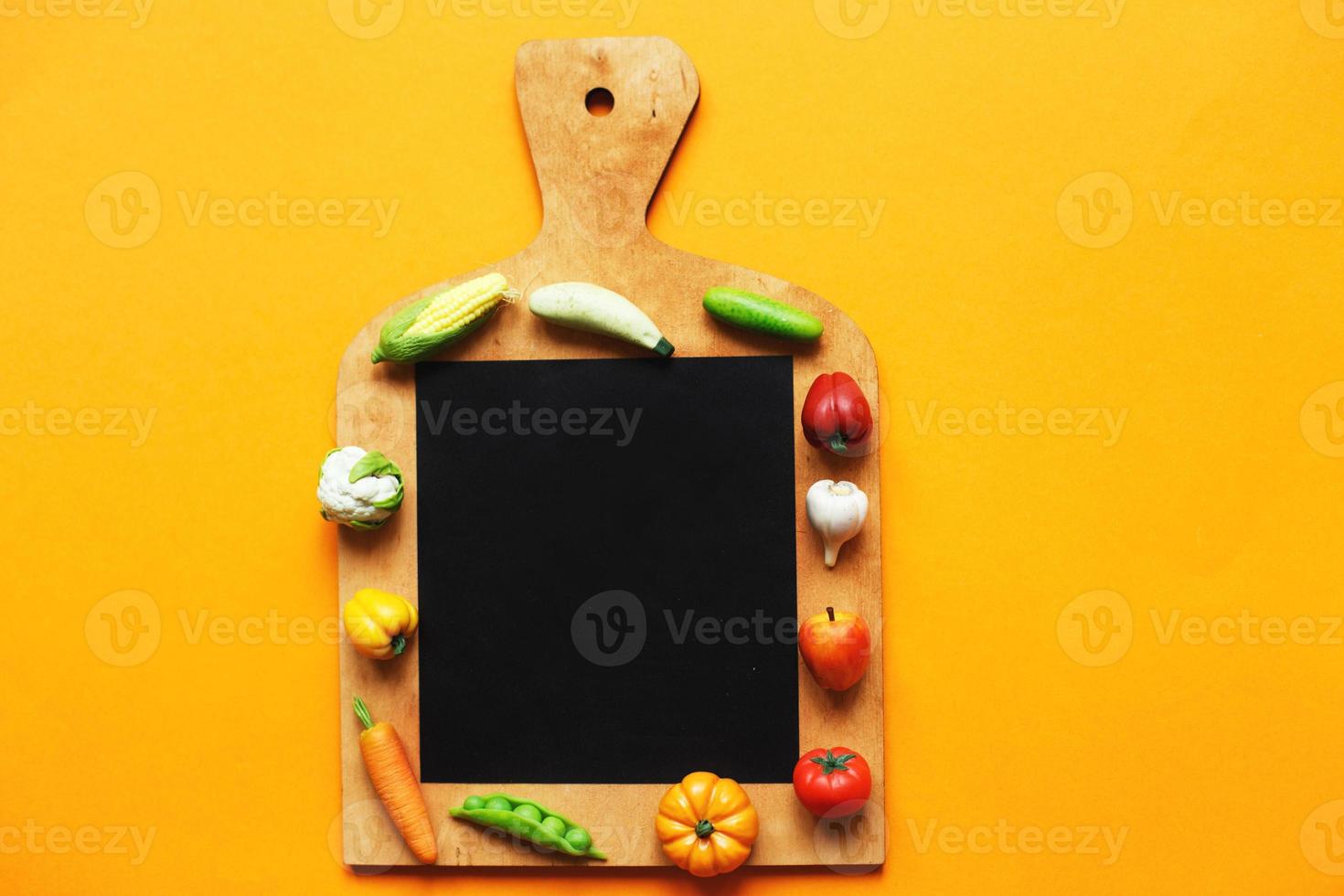 verduras y frutas en la tabla de cortar sobre fondo amarillo. concepto de cocina saludable foto