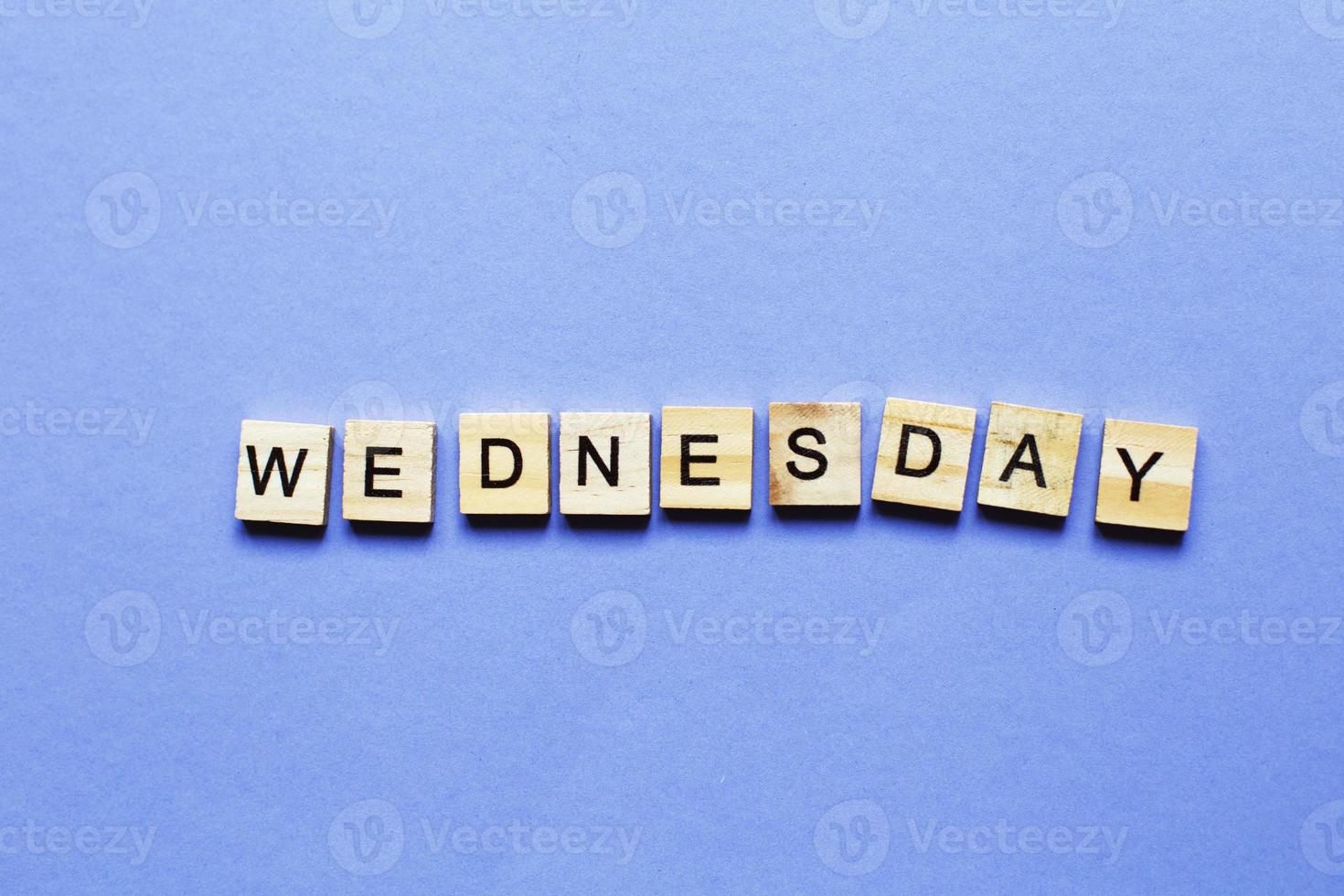 inscription wednesday made by wooden cubes on a veri peri purple background. photo