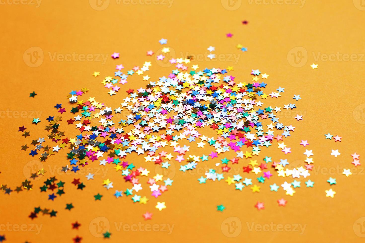 multicolor sparkles on a orange background. Festive backdrop for your projects. photo