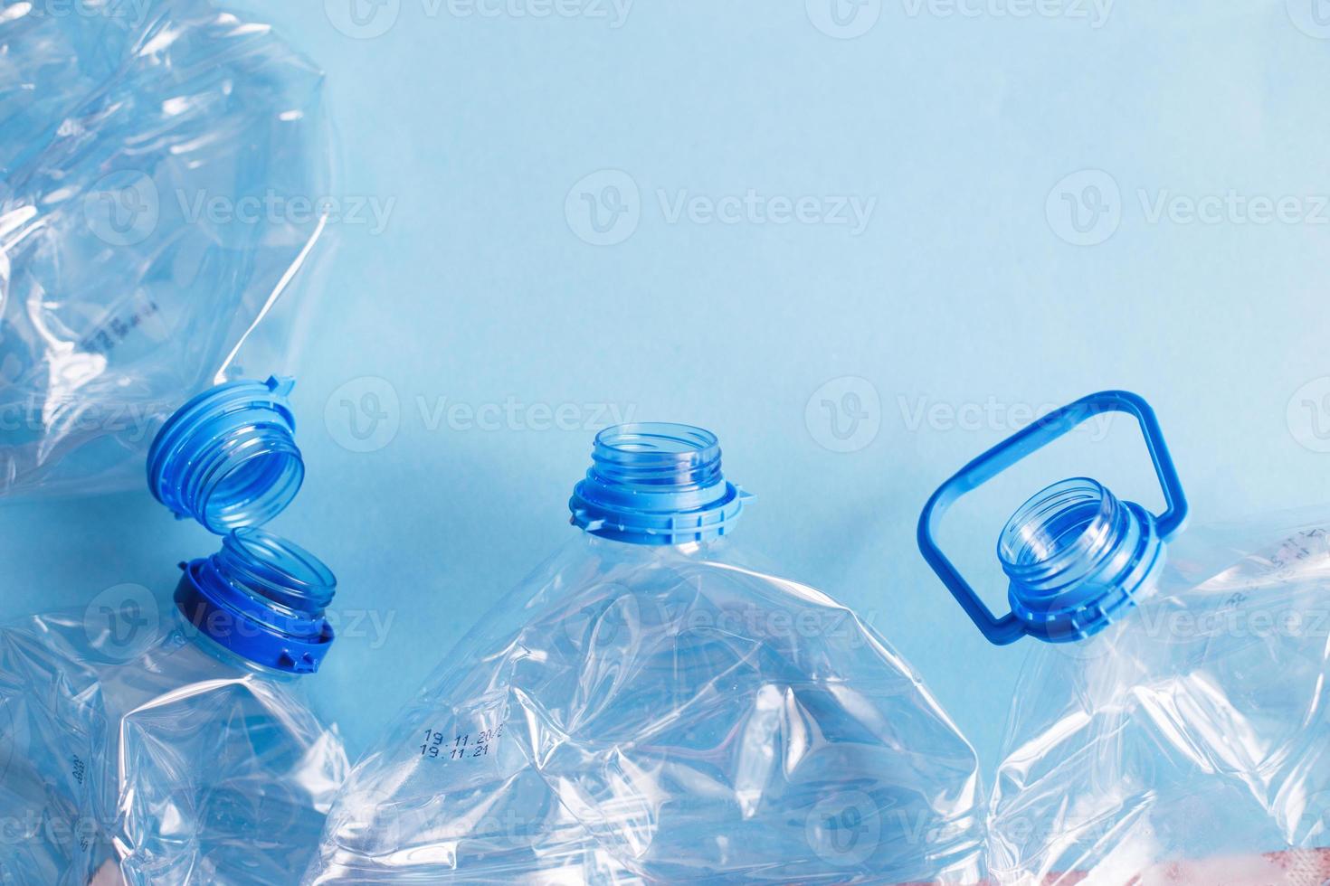a lot of plastic empty rumpled used bottles on a blue background. waste and pollution concept photo
