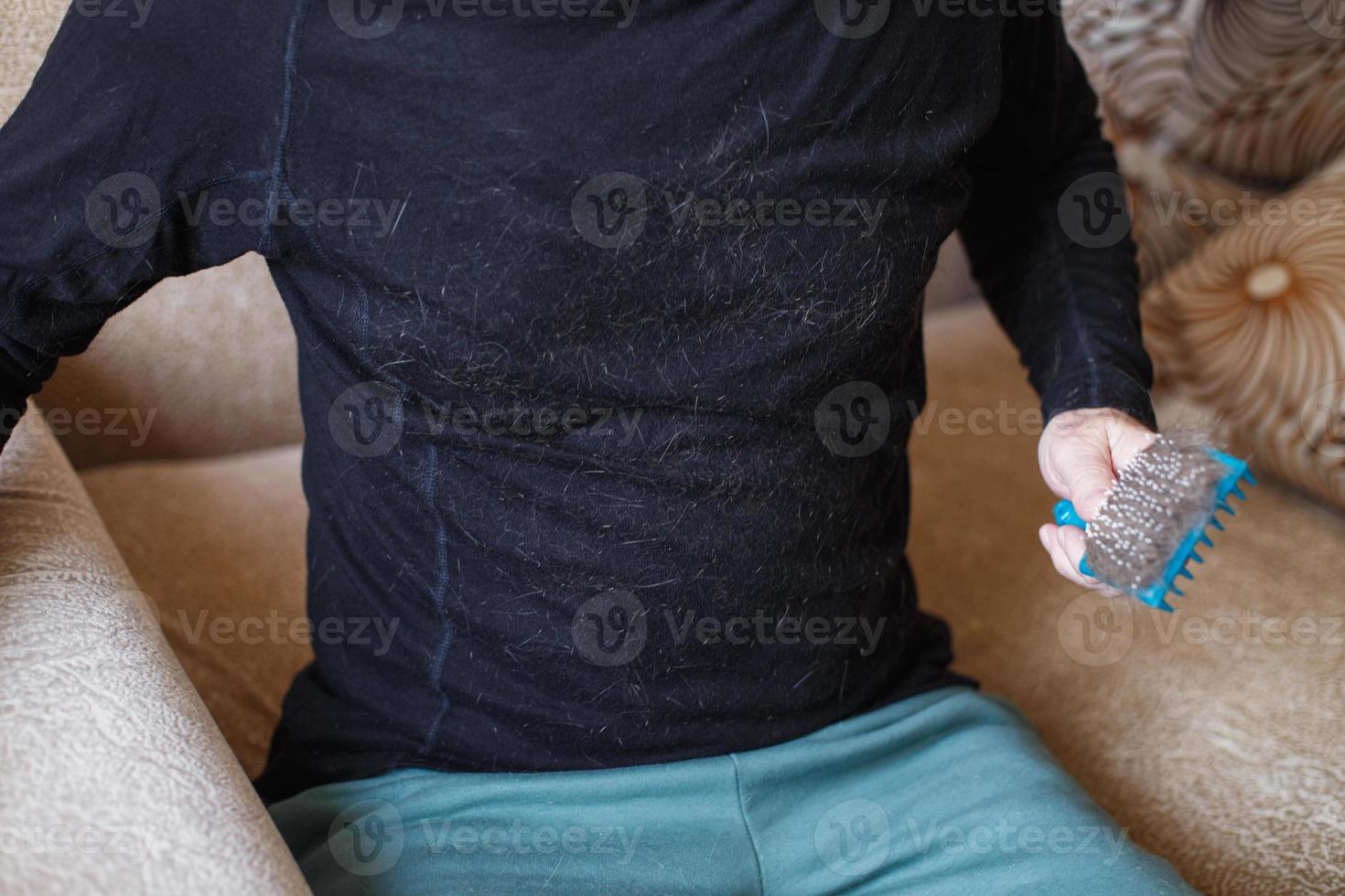 A man's hand holding the cat comb brush with gray fur. photo