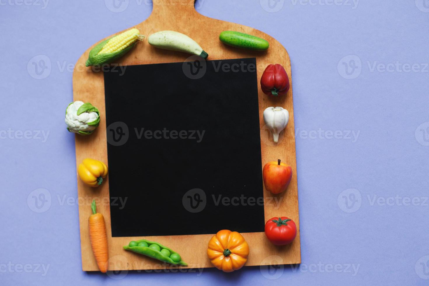 vegetables and fruits on the cutting board on purple background. healthy cooking concept photo