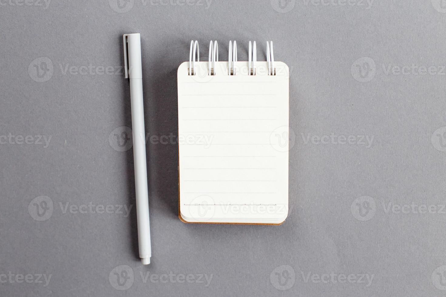 Top view of blank note paper with pen on gray background photo