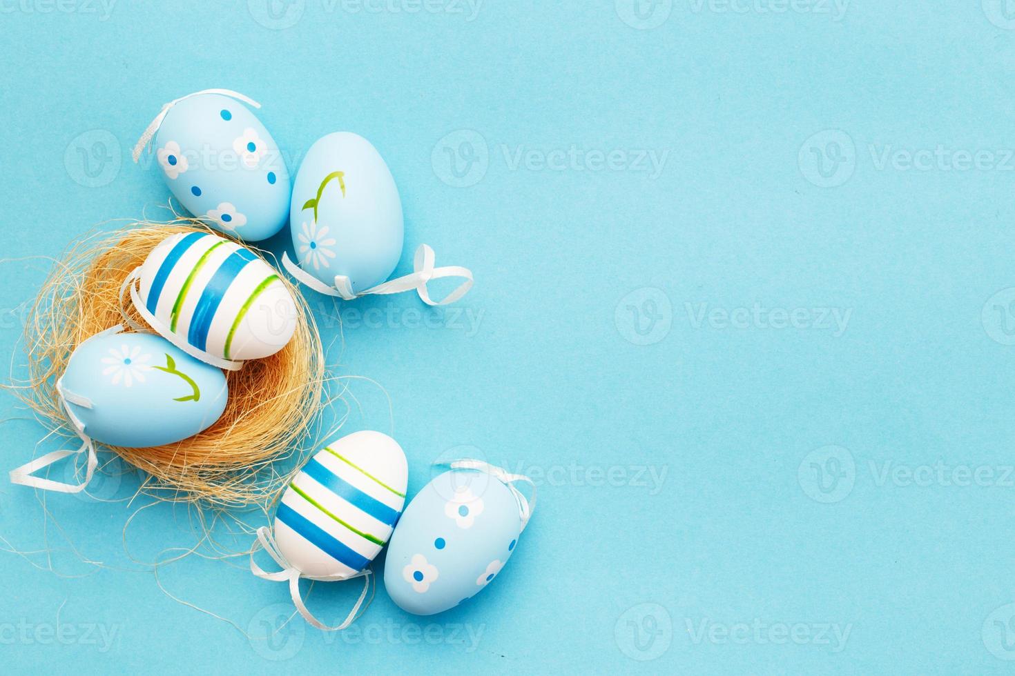 colorful handmade painted eggs in the nest on blue background photo