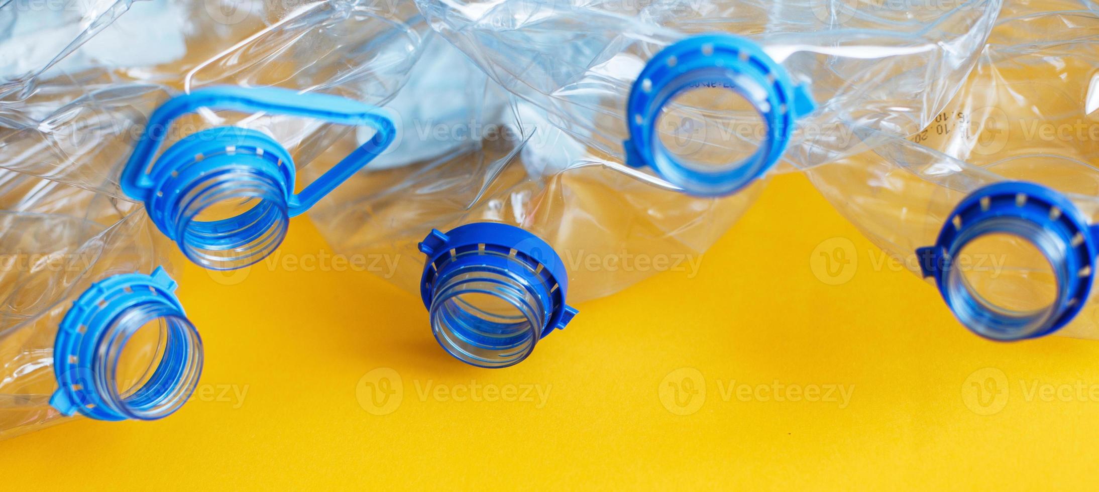 a lot of plastic empty rumpled used bottles on a yellow background. waste and pollution concept photo