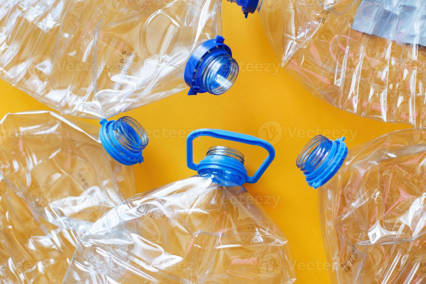 a lot of plastic empty rumpled used bottles on a yellow background. waste and pollution concept photo