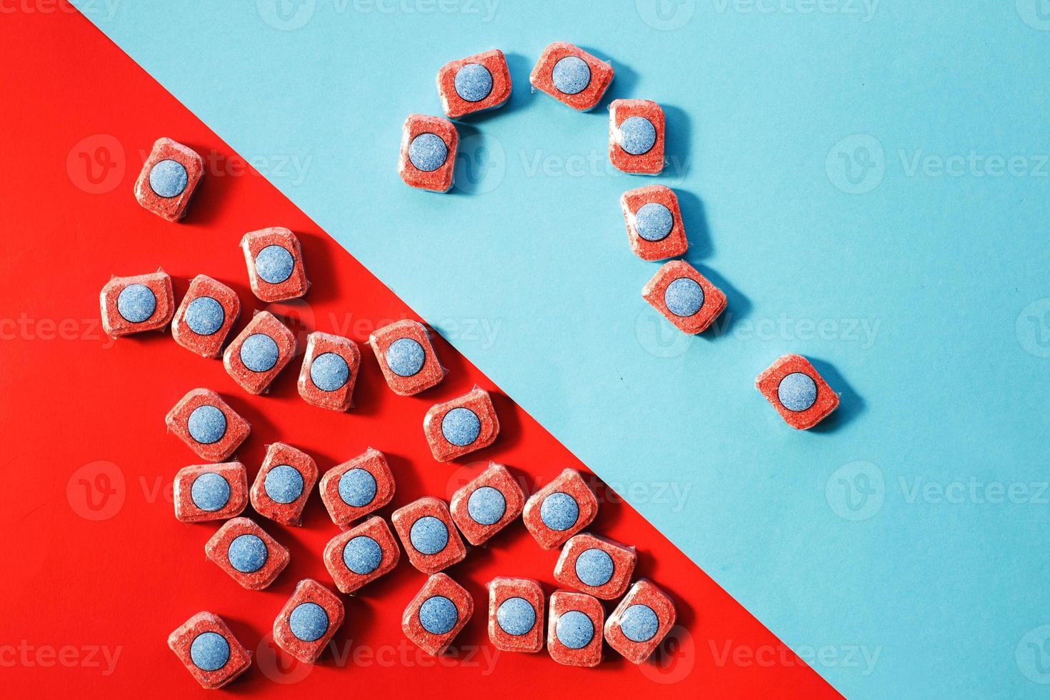 capsules for kitchen dishwashers and a question mark on a blue and red background. flat lay. photo