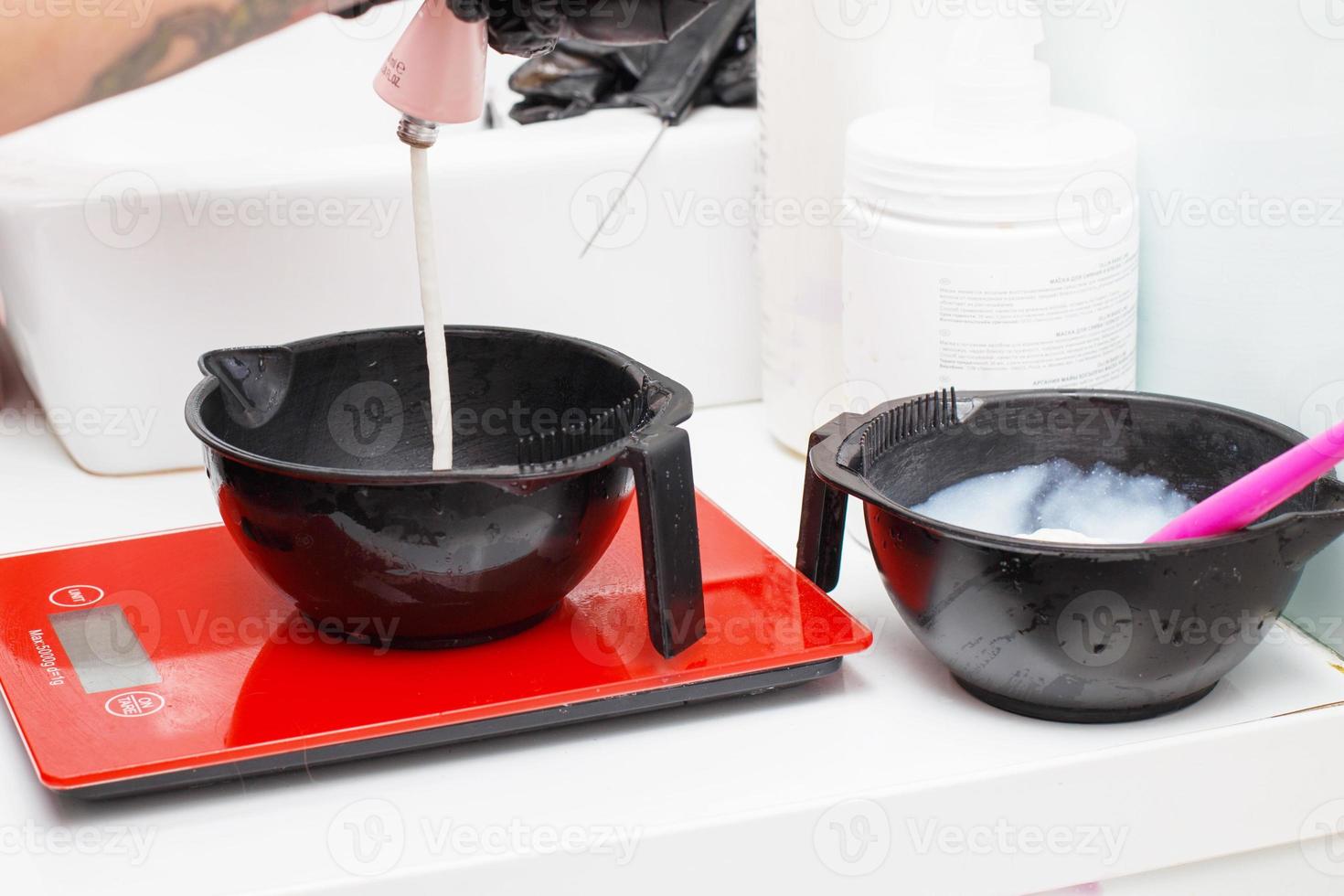 hairdresser holding bowl and preparing hair dye in beauty salon close. photo