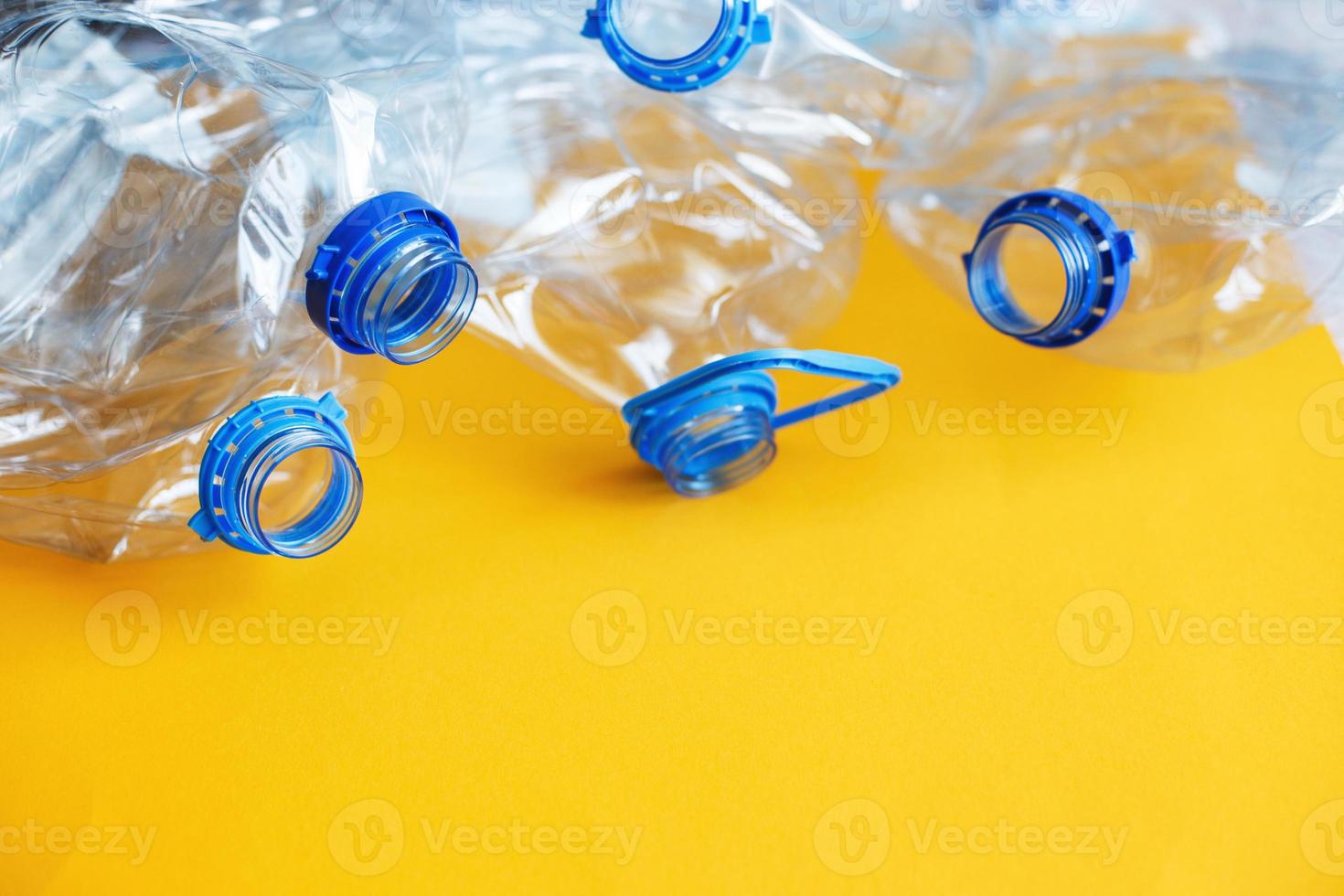 a lot of plastic empty rumpled used bottles on a yellow background. waste and pollution concept photo