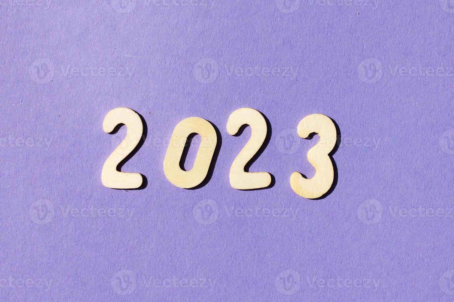 inscription 2023 with wooden numbers on purple background .Festive concept photo