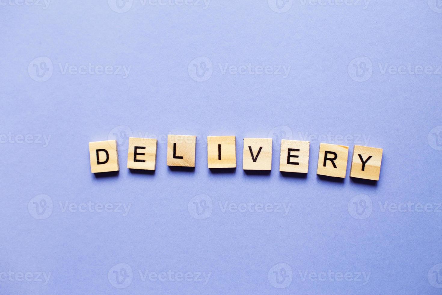 Word delivery made from wooden cubes on a purple paper background. photo