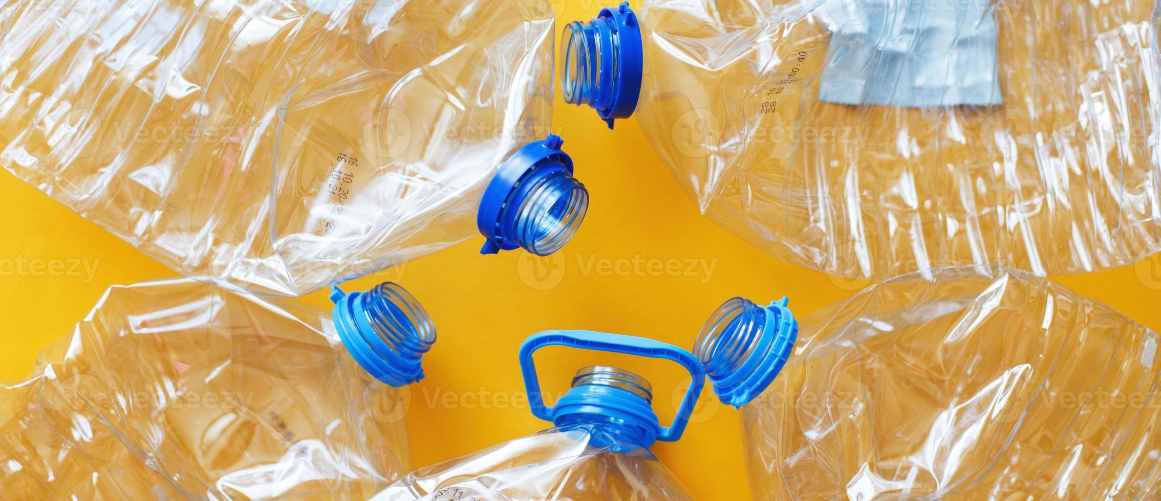 a lot of plastic empty rumpled used bottles on a yellow background. waste and pollution concept photo