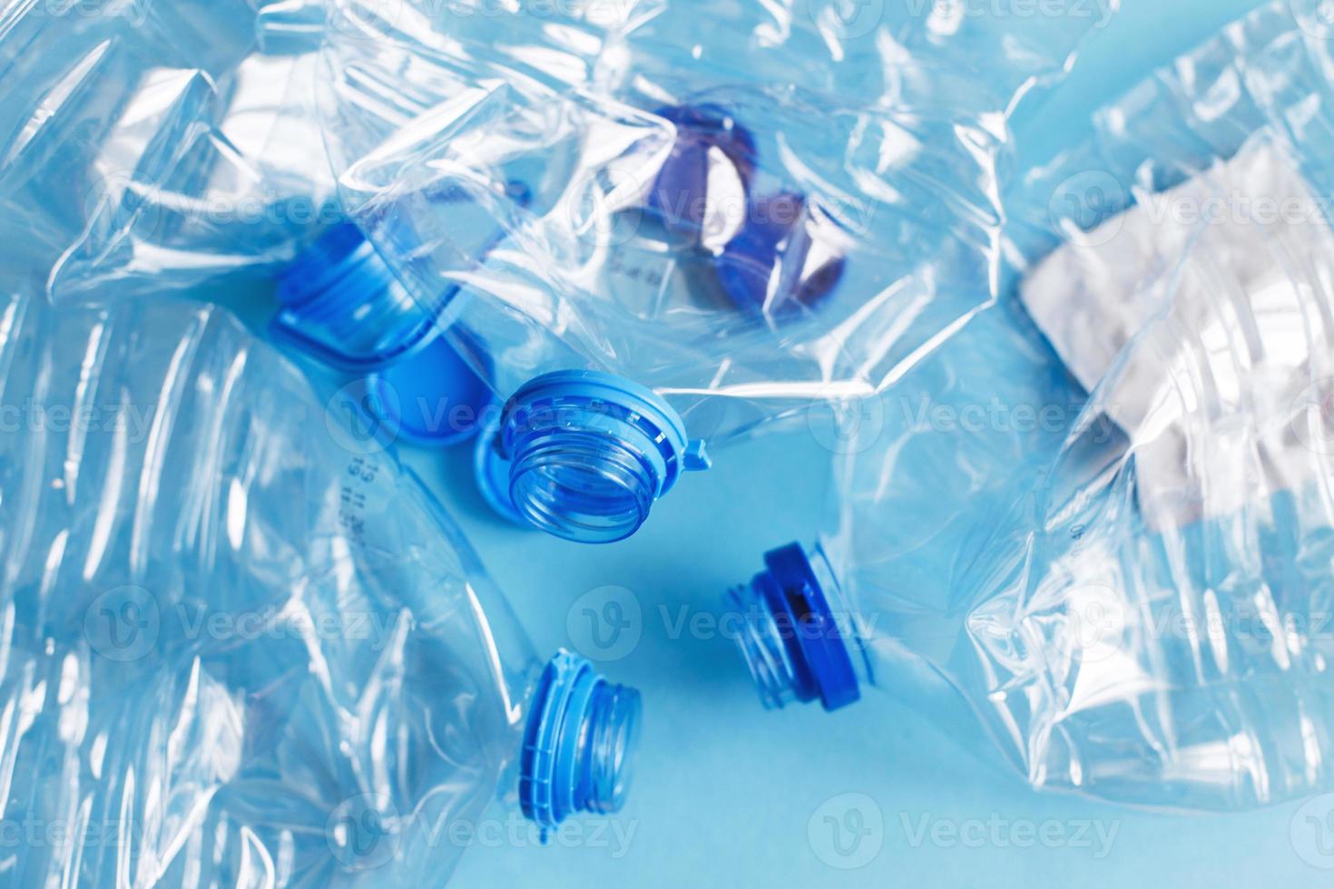 a lot of plastic empty rumpled used bottles on a blue background. waste and pollution concept photo