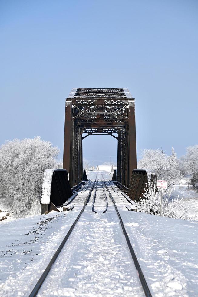 railway tracks in the snow lead to an old bridge photo