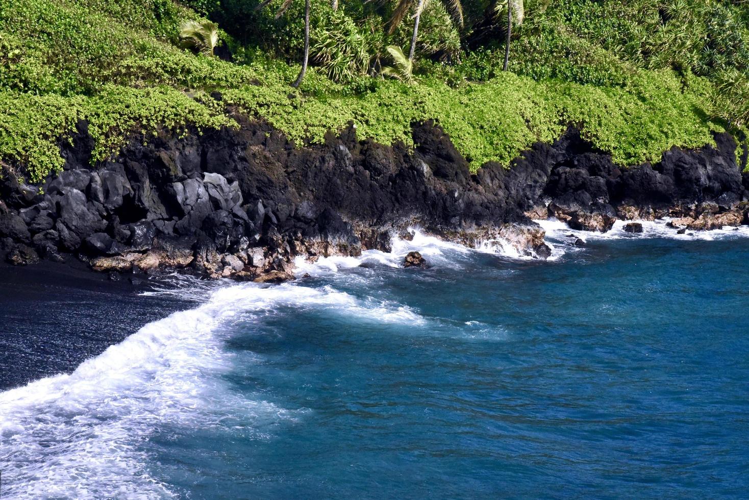 una playa de arena negra en maui foto