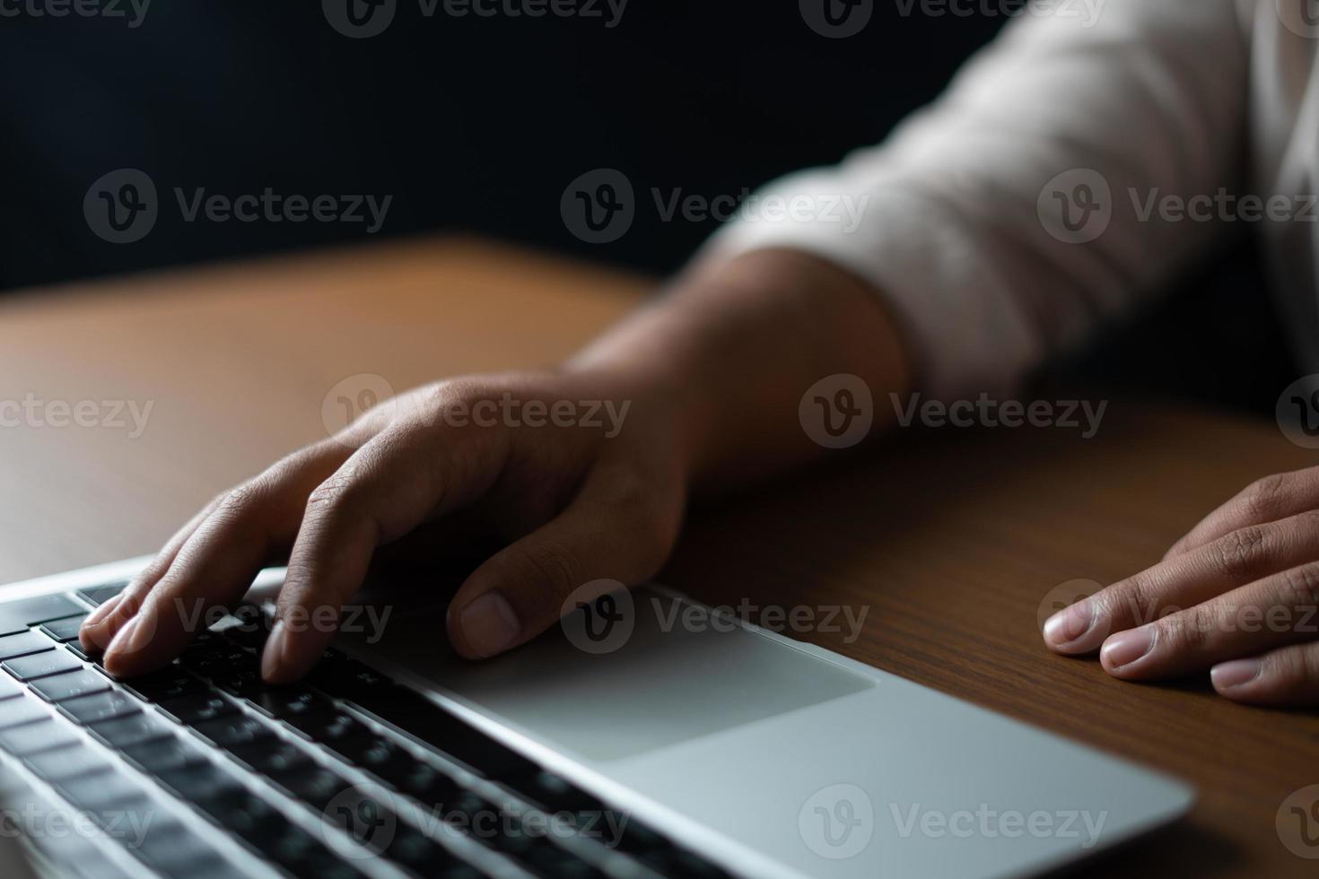 hombre de negocios escribiendo en una computadora portátil en una habitación oscura foto