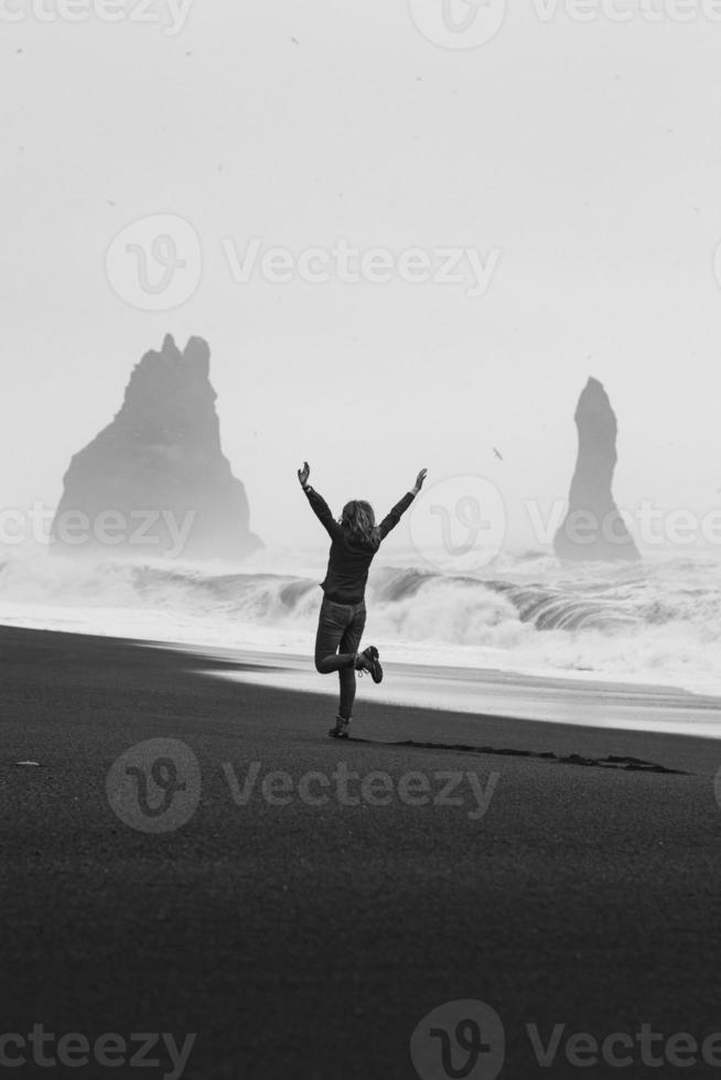 turista emocionado en la fotografía escénica monocromática de la playa negra vacía foto